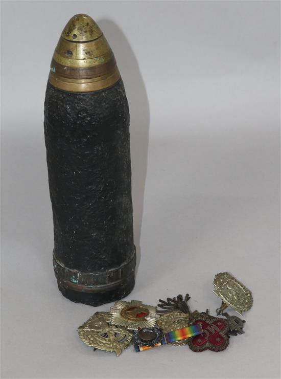 Militaria. A shell casing and Boer War and later Scottish cap badges.